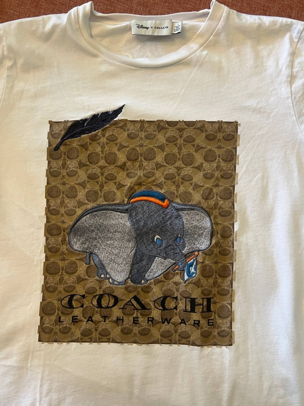 Disney x Coach collab tee featuring embroidered Dumbo on signature logo patch